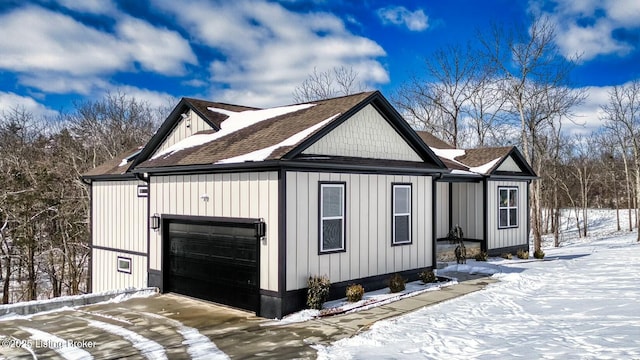 view of snowy exterior with roof with shingles, board and batten siding, and an attached garage