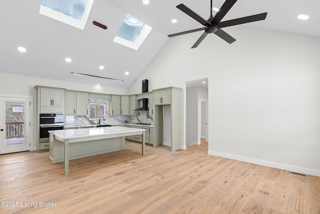 kitchen with a kitchen breakfast bar, a center island, light countertops, light wood-type flooring, and wall chimney range hood