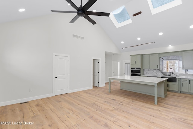 kitchen with a breakfast bar area, a skylight, a kitchen island, visible vents, and light countertops