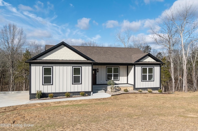 view of front of property with board and batten siding, a front yard, a shingled roof, and a porch