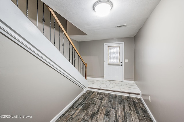 foyer with dark hardwood / wood-style flooring and a textured ceiling