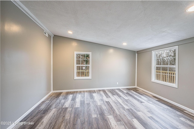 unfurnished room with hardwood / wood-style floors, vaulted ceiling, and a textured ceiling