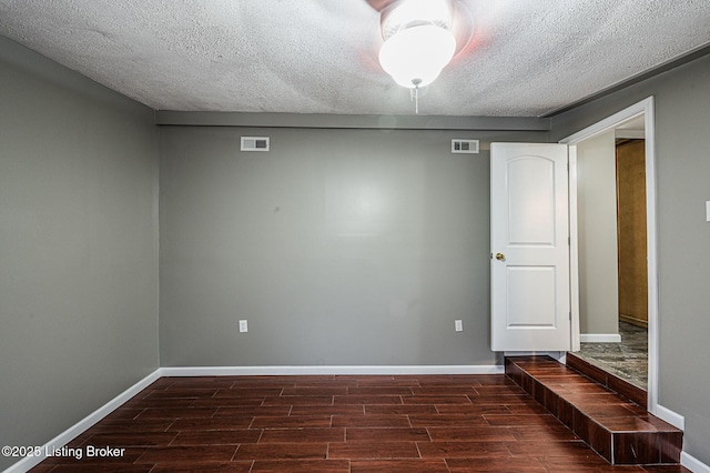 unfurnished room featuring a textured ceiling and dark wood-type flooring