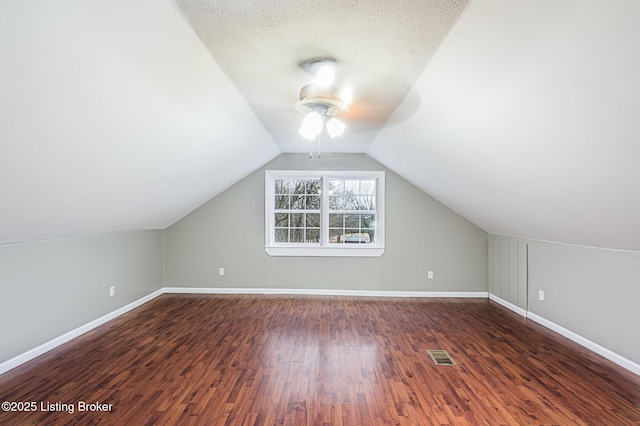 bonus room with dark wood-type flooring, a textured ceiling, and lofted ceiling