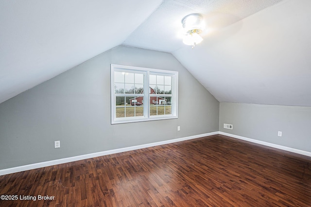 additional living space featuring lofted ceiling and dark wood-type flooring