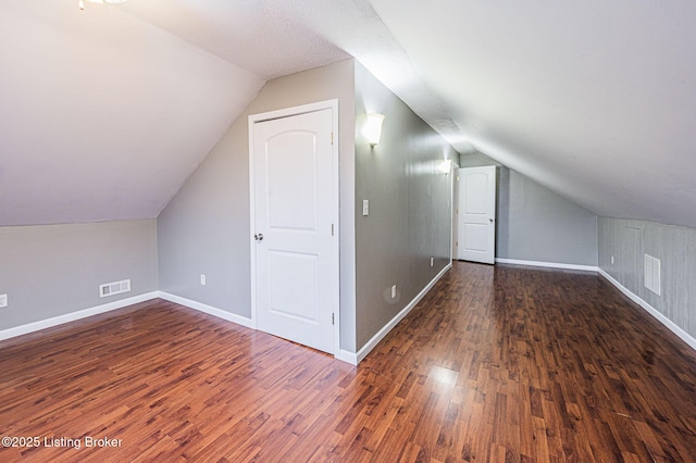 additional living space with vaulted ceiling and dark hardwood / wood-style flooring