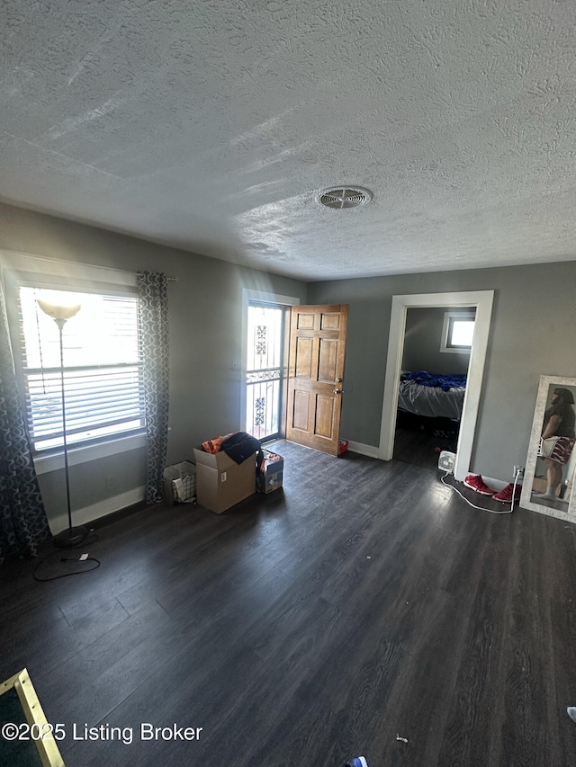 interior space with a textured ceiling, dark hardwood / wood-style floors, and a wealth of natural light