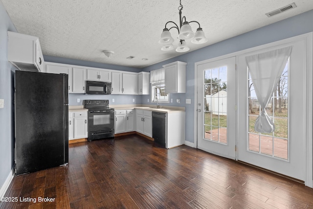 kitchen featuring dark wood-style flooring, a sink, visible vents, light countertops, and black appliances