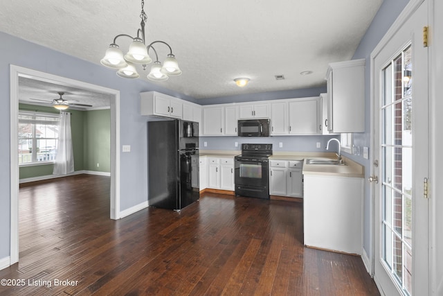 kitchen with baseboards, dark wood-type flooring, light countertops, black appliances, and a sink