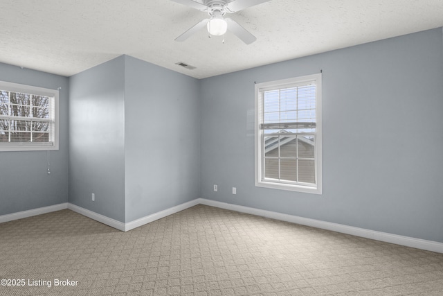 empty room with a ceiling fan, visible vents, baseboards, and a textured ceiling