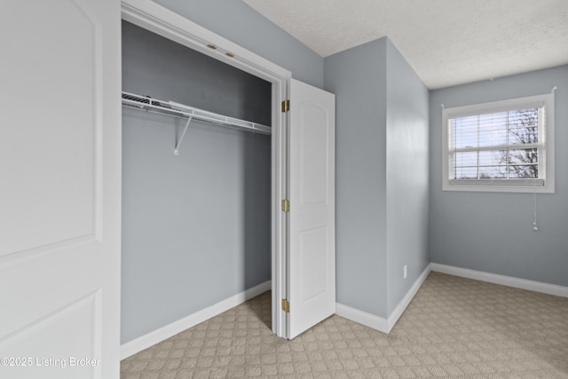 unfurnished bedroom featuring a textured ceiling, a closet, and baseboards