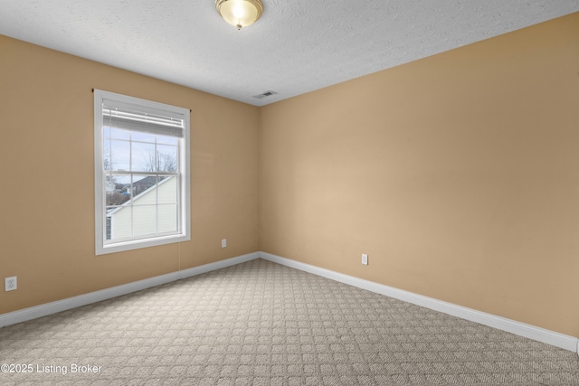 spare room featuring baseboards, visible vents, a textured ceiling, and carpet flooring