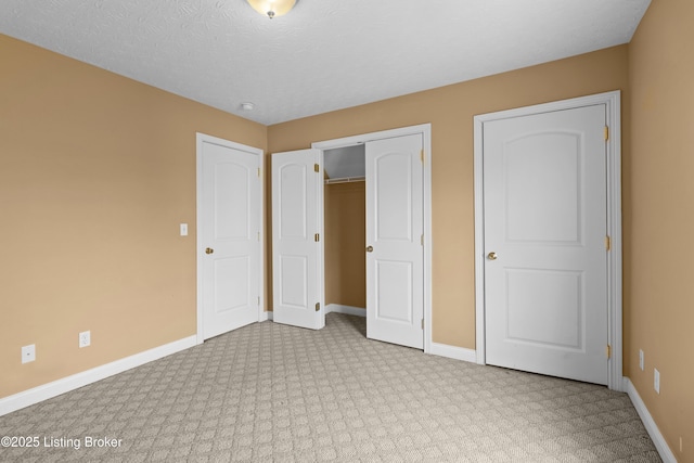 unfurnished bedroom featuring a textured ceiling, a closet, and baseboards