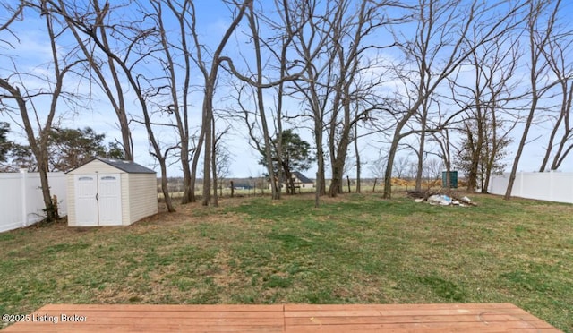 view of yard featuring a fenced backyard, a storage unit, and an outbuilding