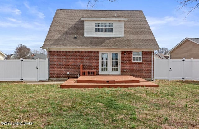 back of house featuring brick siding, a gate, a lawn, and french doors