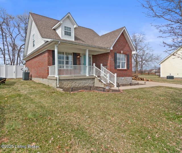 view of front of house with a front yard, fence, a porch, and brick siding