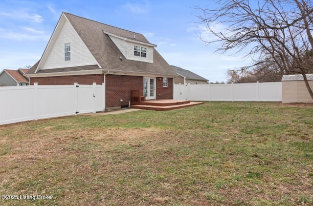 back of house featuring an outbuilding, a fenced backyard, brick siding, a yard, and a shed