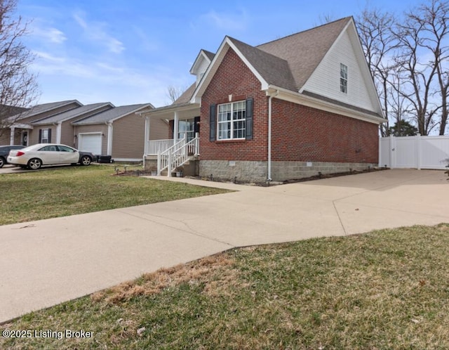 view of front of home featuring brick siding, driveway, crawl space, a gate, and a front yard