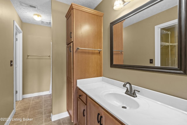 bathroom featuring tile patterned flooring, visible vents, a textured ceiling, and vanity