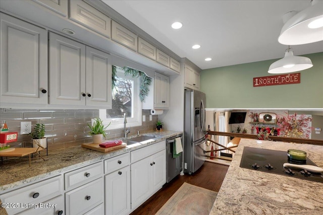 kitchen with hanging light fixtures, dark hardwood / wood-style floors, appliances with stainless steel finishes, light stone countertops, and sink