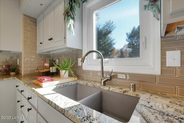 kitchen featuring sink, backsplash, and white cabinets