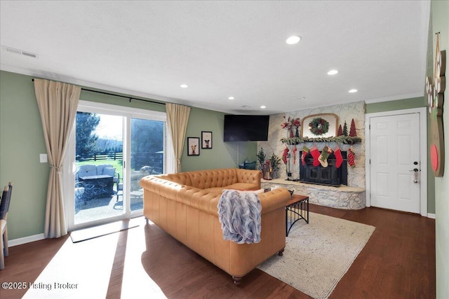 living room with a stone fireplace and dark wood-type flooring