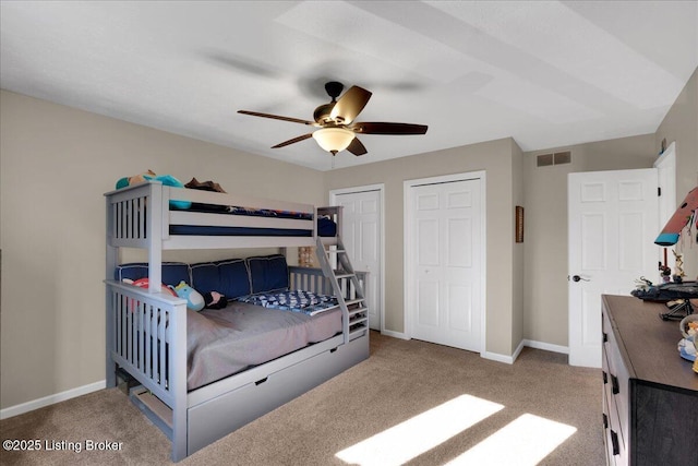 carpeted bedroom featuring two closets and ceiling fan