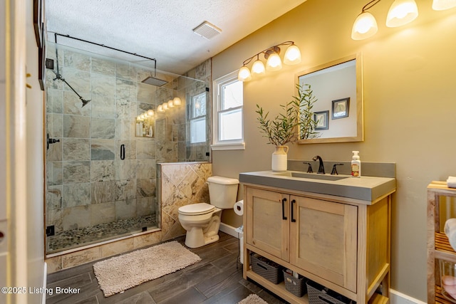 full bathroom with a textured ceiling, wood finish floors, vanity, visible vents, and a stall shower