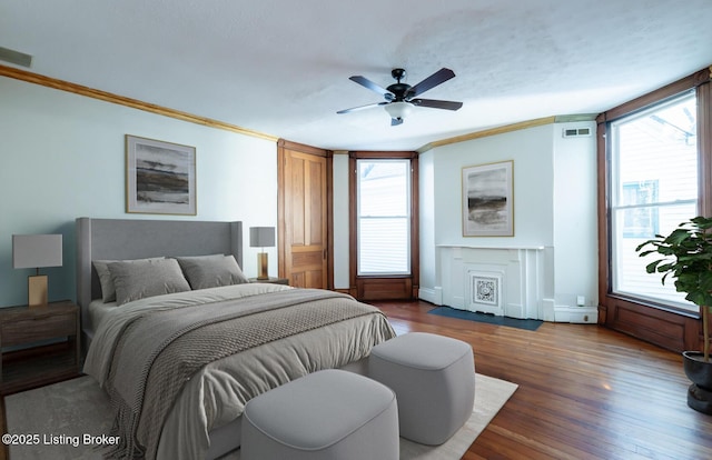 bedroom with ceiling fan, ornamental molding, multiple windows, and dark hardwood / wood-style floors