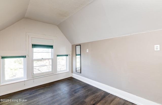 additional living space featuring vaulted ceiling and dark hardwood / wood-style flooring