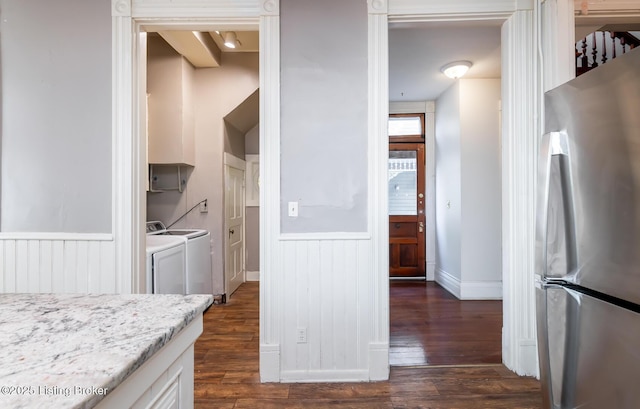 kitchen with white cabinetry, stainless steel refrigerator, light stone counters, dark wood-type flooring, and washer and clothes dryer