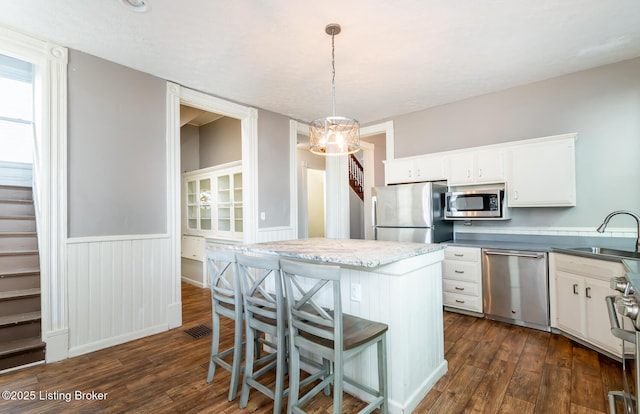 kitchen with appliances with stainless steel finishes, sink, pendant lighting, dark hardwood / wood-style floors, and white cabinets