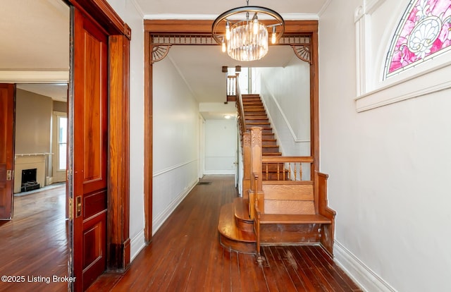 stairway featuring a notable chandelier, ornamental molding, and wood-type flooring