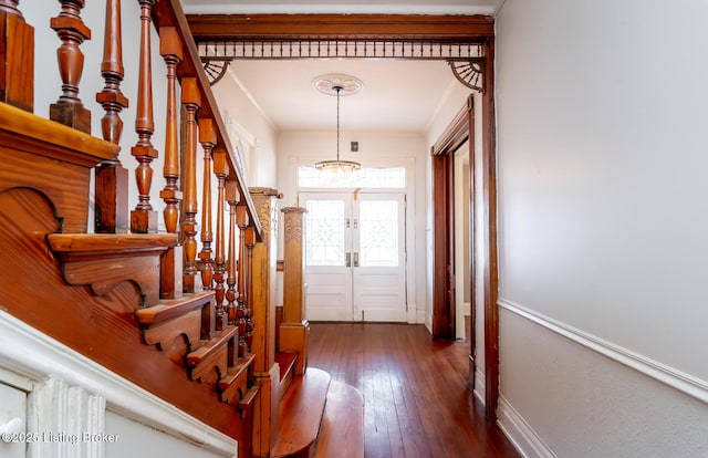 entryway featuring dark hardwood / wood-style flooring, crown molding, french doors, and an inviting chandelier