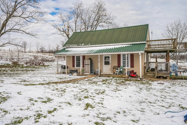 snow covered rear of property with a porch