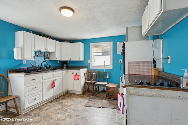 kitchen with a textured ceiling, sink, white cabinets, and black electric cooktop