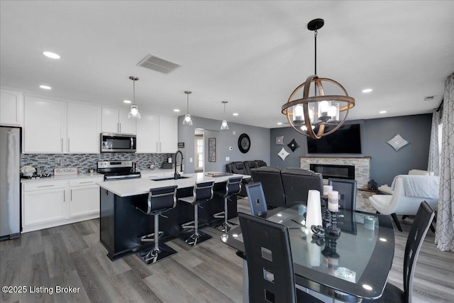 dining area featuring sink, hardwood / wood-style flooring, an inviting chandelier, and a fireplace