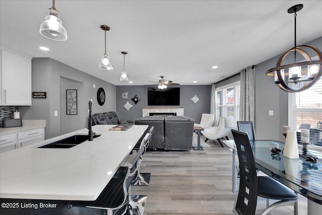 dining room with sink, ceiling fan with notable chandelier, and light hardwood / wood-style flooring