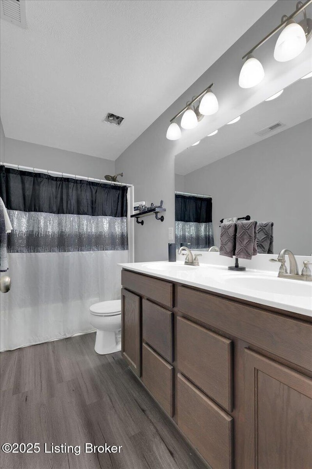 bathroom featuring hardwood / wood-style floors, vanity, a shower with shower curtain, and toilet