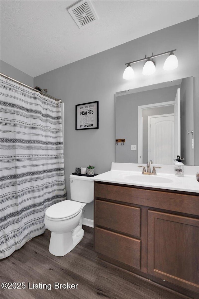 bathroom featuring toilet, a textured ceiling, curtained shower, hardwood / wood-style floors, and vanity