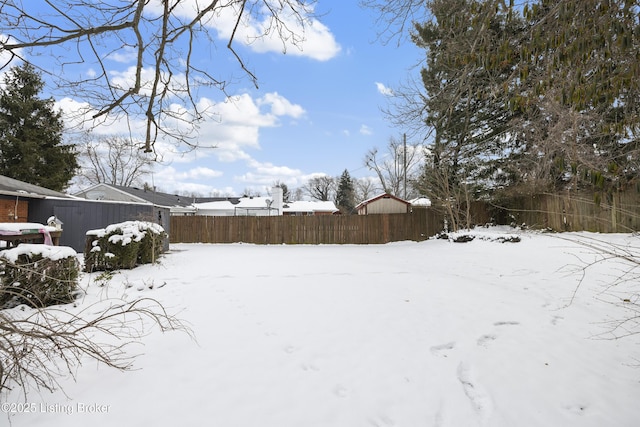 snowy yard with a fenced backyard