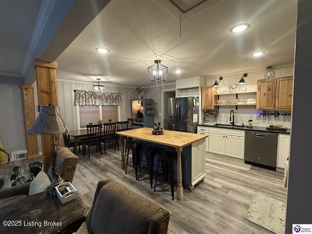 kitchen with butcher block counters, dishwasher, stainless steel refrigerator, a center island, and sink