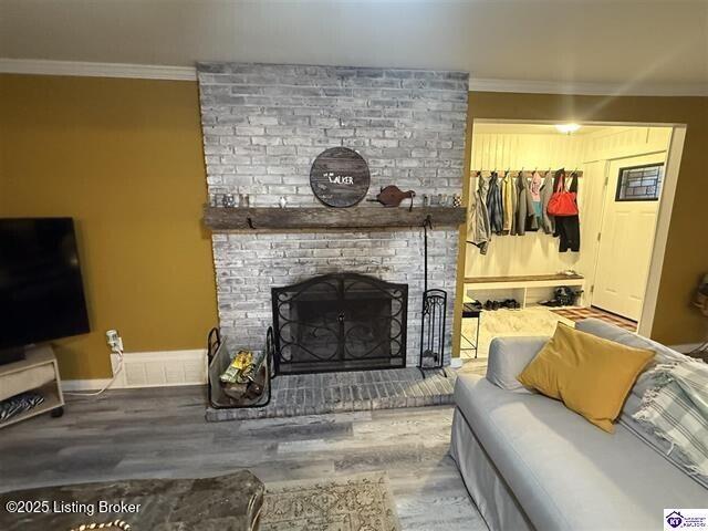 living room featuring a brick fireplace, hardwood / wood-style flooring, and ornamental molding