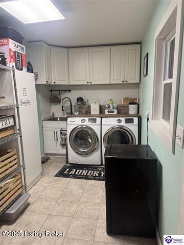 laundry area with cabinets, light tile patterned floors, sink, and washing machine and clothes dryer