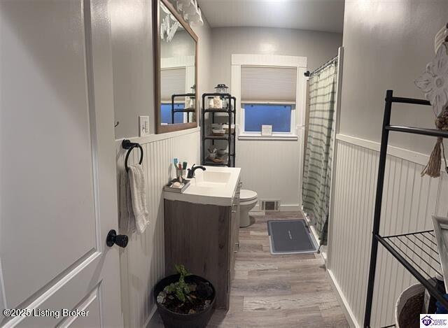 bathroom with curtained shower, vanity, toilet, and hardwood / wood-style floors