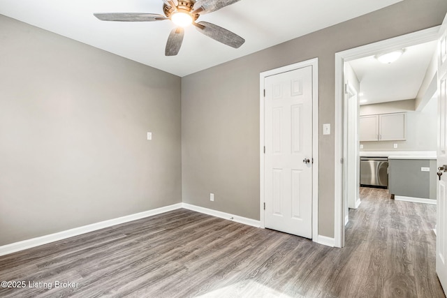 spare room with wood finished floors, a ceiling fan, and baseboards