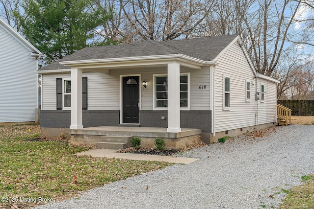 bungalow-style house with crawl space, a porch, a shingled roof, and brick siding