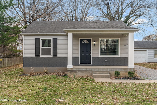 bungalow-style home with brick siding, a shingled roof, fence, a porch, and a front yard