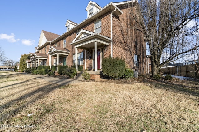 view of front of property with brick siding, a front lawn, and fence