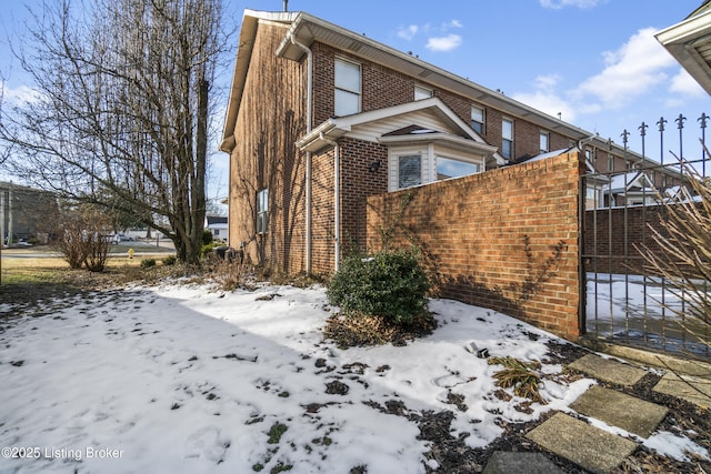 view of snow covered exterior with brick siding